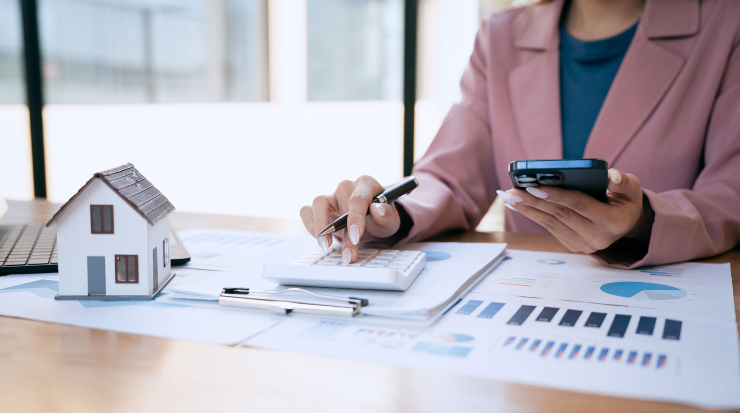 Vue de dessus d'un bureau avec trois offres de crédit immobilier côte à côte annotées au surligneur, accompagnées d'une calculatrice et d'un smartphone